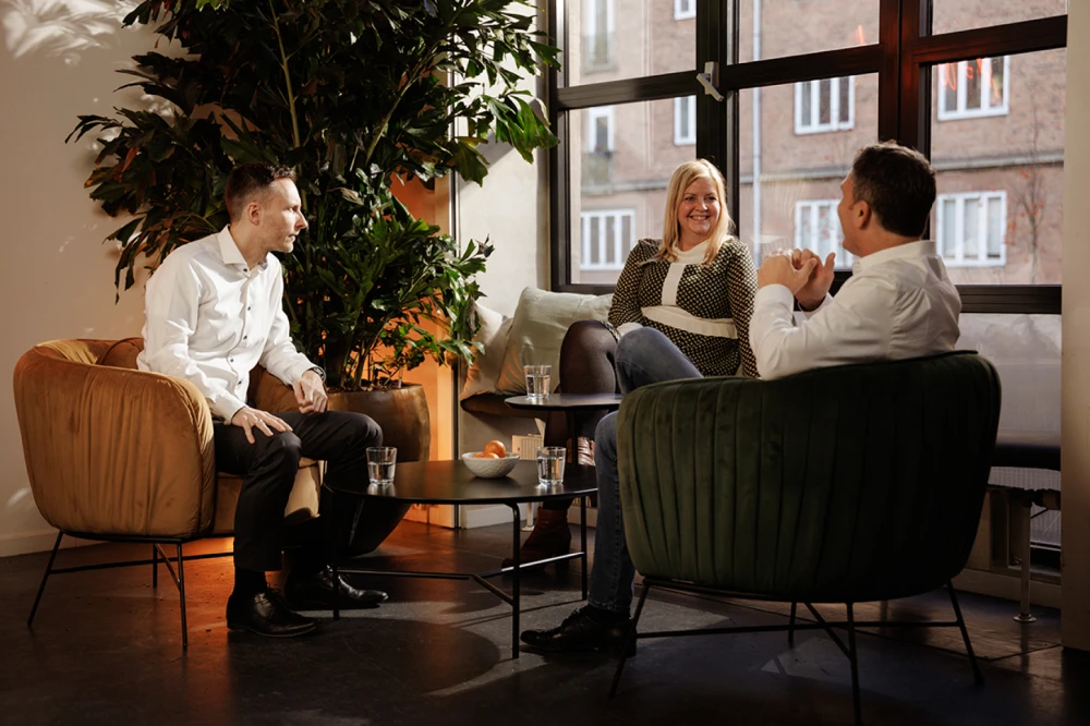 Three company leaders sitting together by a window having a friendly conversation in an office