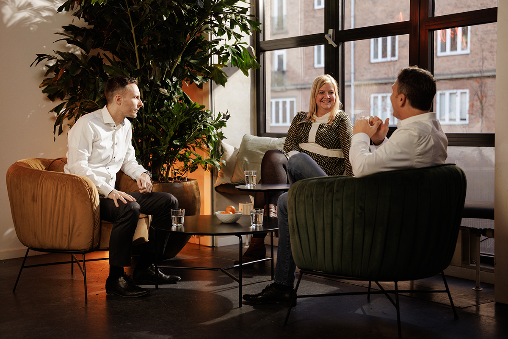 Three company leaders sitting together by a window having a friendly conversation in an office