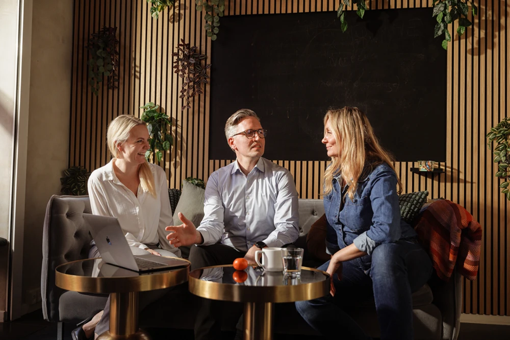 Three colleagues collaborating while sitting and looking at a laptop