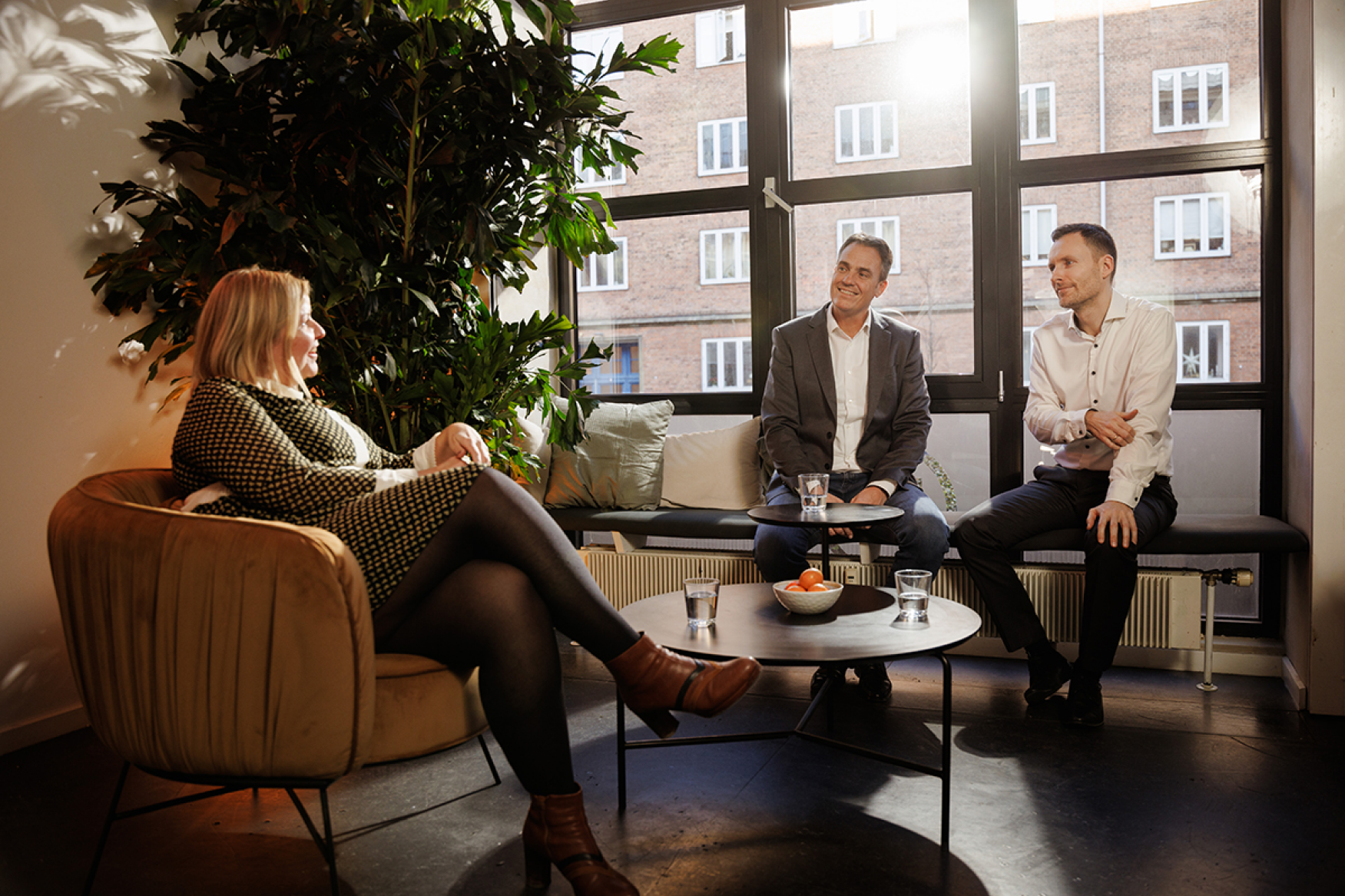 Three company leaders sitting together by a window having a friendly conversation in an office