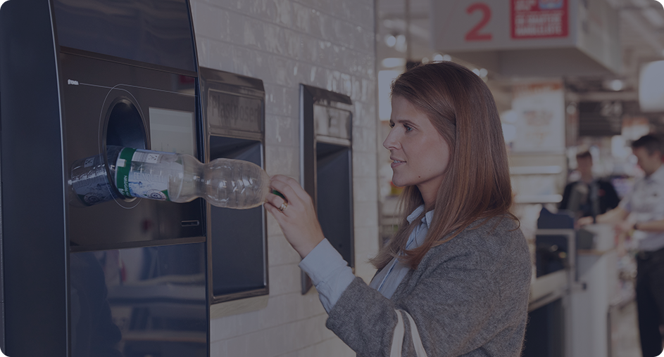 Customer recycling a plastic bottle at reverse vending machine