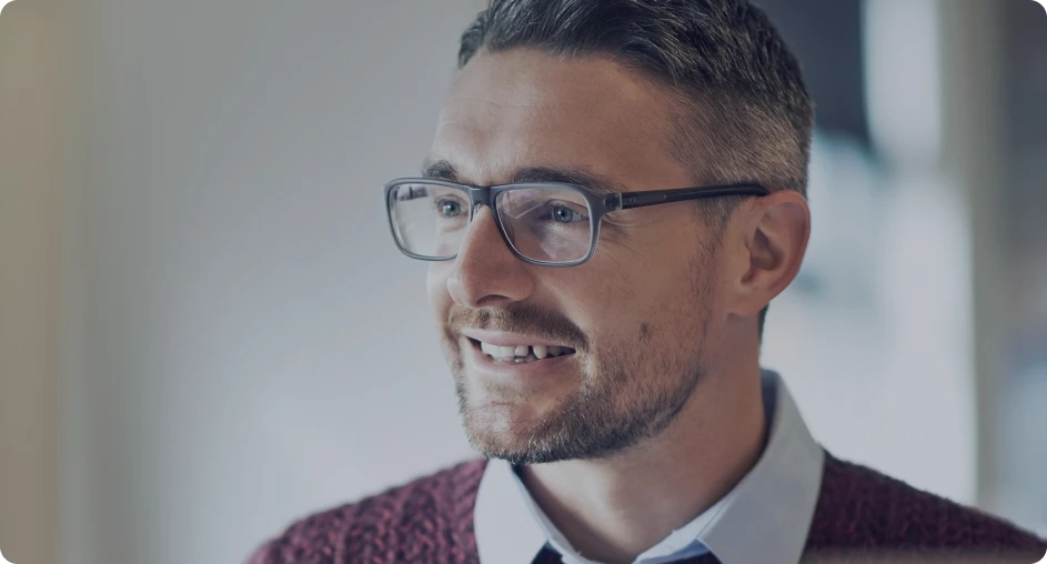 Close-up of a man with glasses and a beard smiling