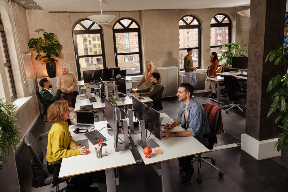 A team working at their desks in an open concept office having dialogues over the tables with each other