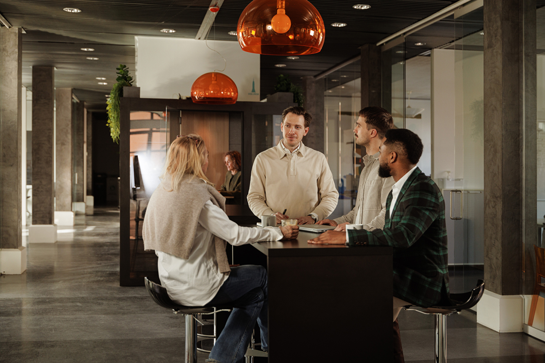 Colleagues in a causal conversation at a high table in the office